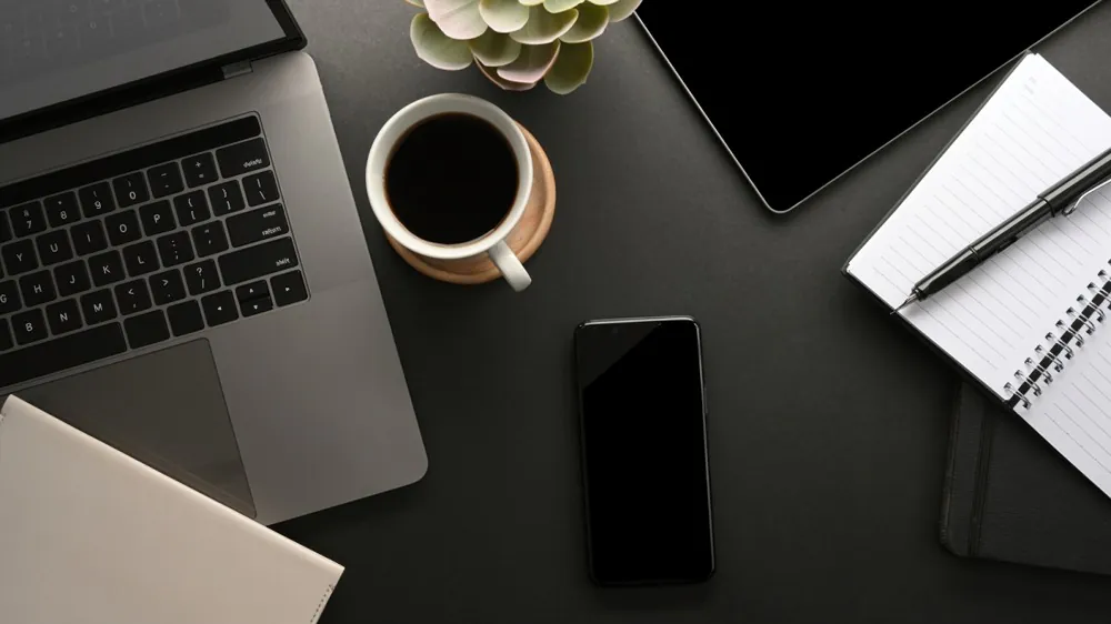 Desk with laptop, phone notepad, and coffee cup